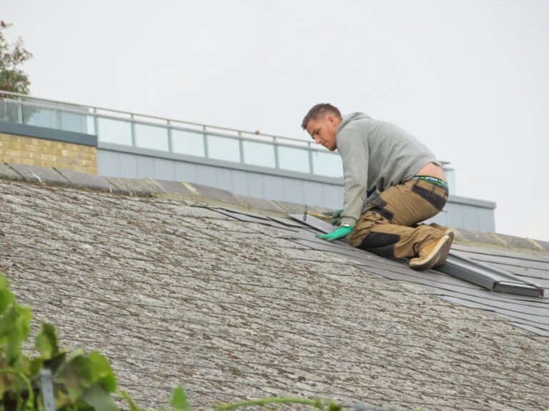 Construction worker installing shingles on a sloped rooftop, demonstrating roofing techniques relevant to THP Roofing of Knoxville's services.