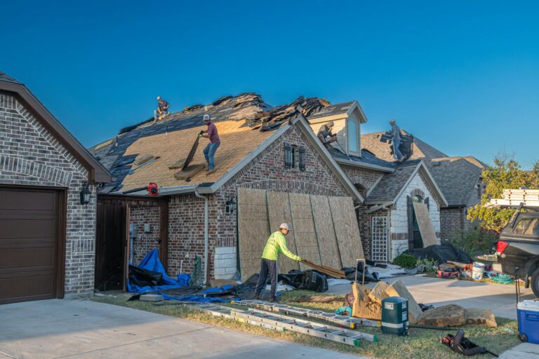 Workers engaged in roof replacement on a residential home, showcasing roofing materials and equipment in Knoxville.