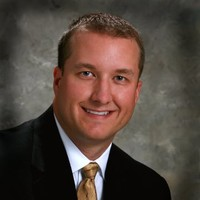 Troy Peterson, founder of Guardian Roofing of Knoxville, smiling in a professional suit, emphasizing trust and expertise in roofing services.