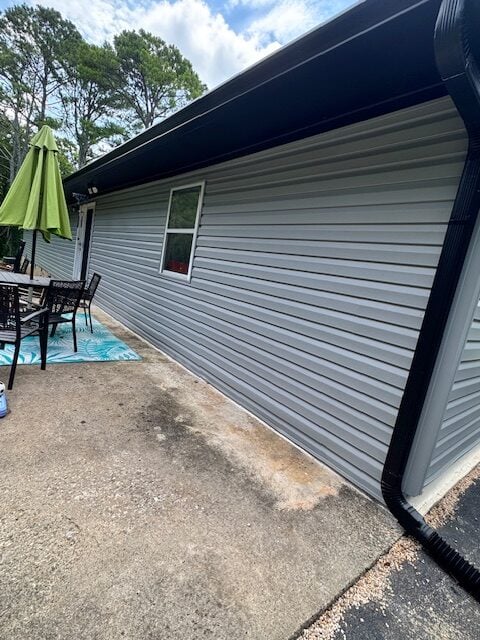 Seamless siding installation on a residential home in Knoxville, featuring a gray exterior, window, and adjacent patio area with furniture and an umbrella.